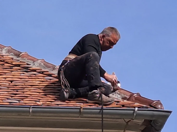 Couvreur de FM Couverture 77 réalisant une intervention de finition sur une toiture en tuiles avec équipement de sécurité