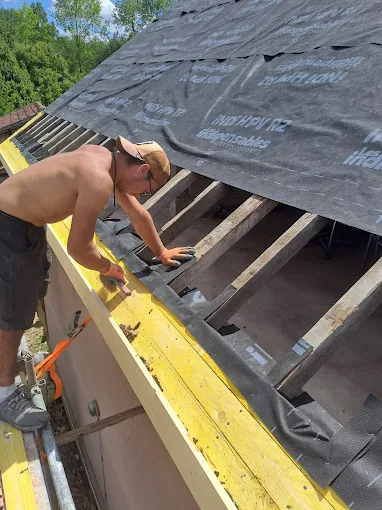 Couvreur de FM Couverture 77 posant un écran de sous-toiture sur une charpente apparente lors d’une rénovation de toiture