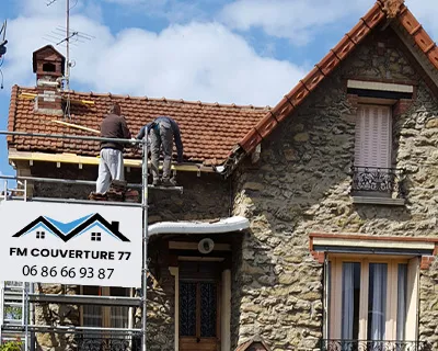 Couvreurs intervenant sur la rénovation d’une toiture en tuiles sur une maison en pierre en Seine-et-Marne (77)